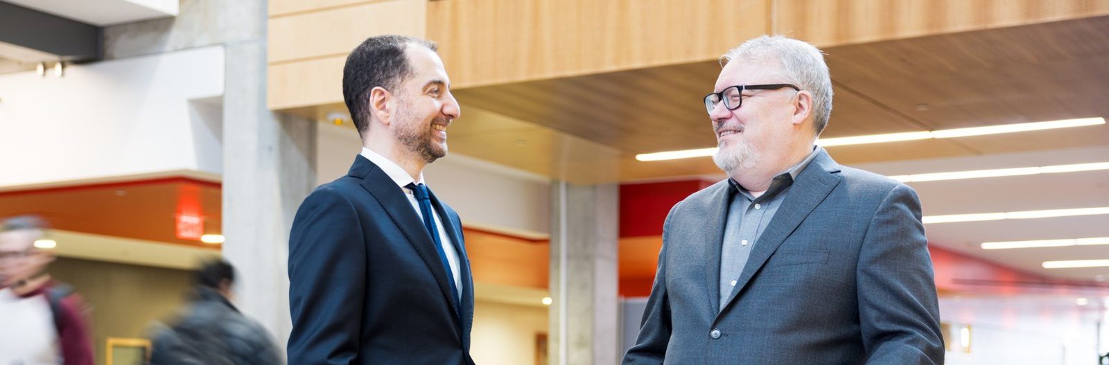 Panos Panagiotakopoulos and Kent Peel talking in a sunlit atrium